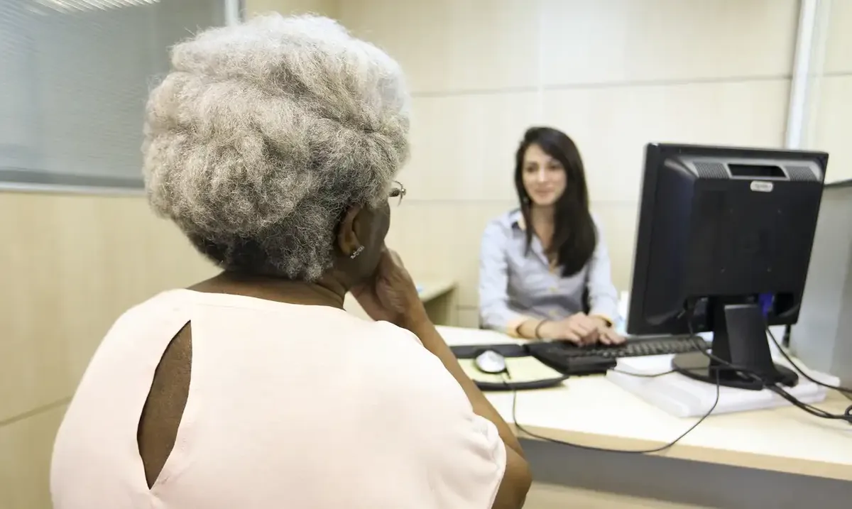 Idosa em atendimento para solicitação do BPC em uma unidade de serviço social.